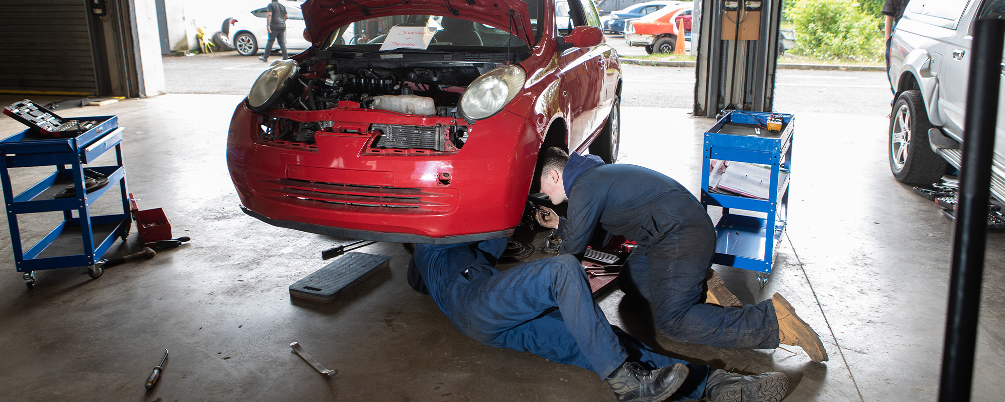 Two automotive students working on a car