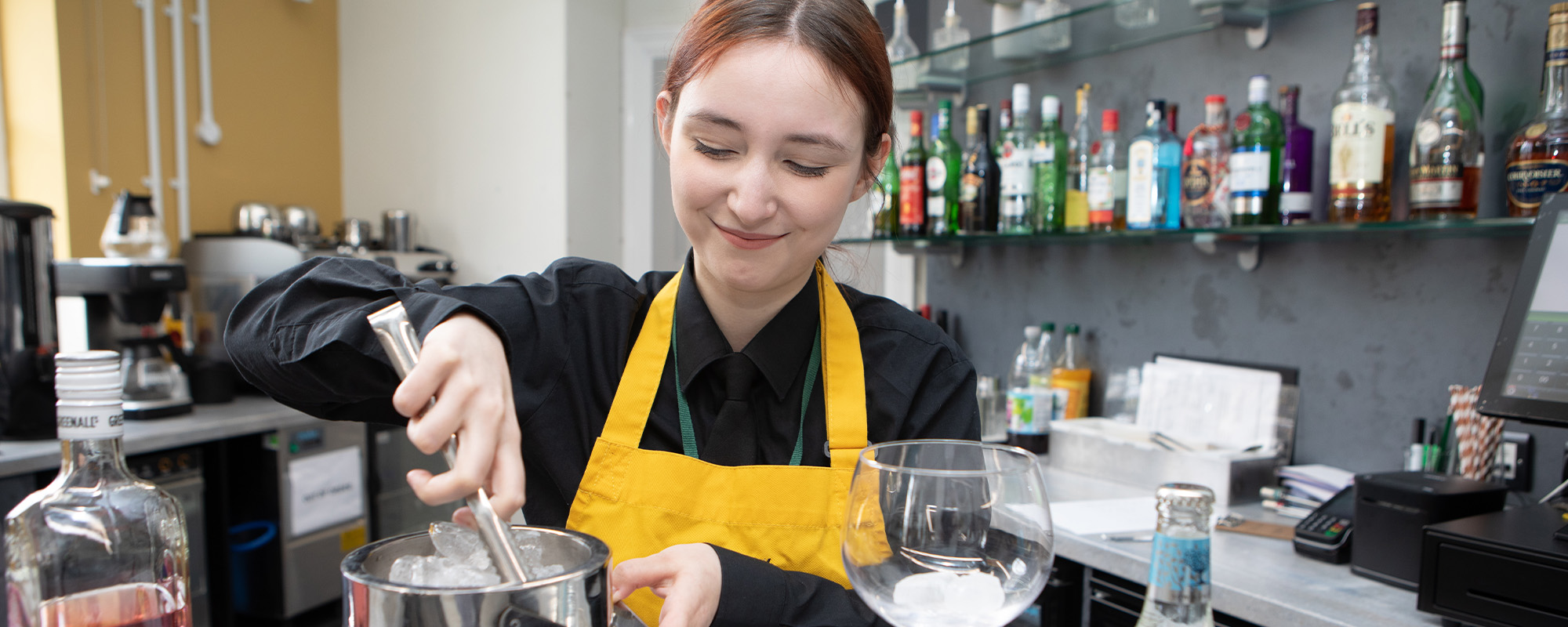 A student serving drinks behind the bar 