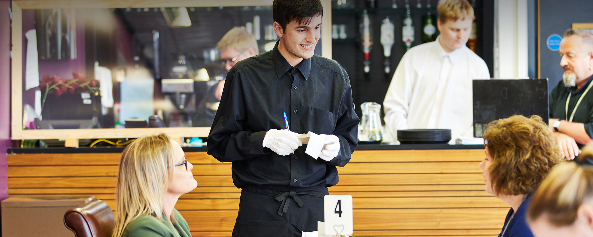 A student taking orders from some customers