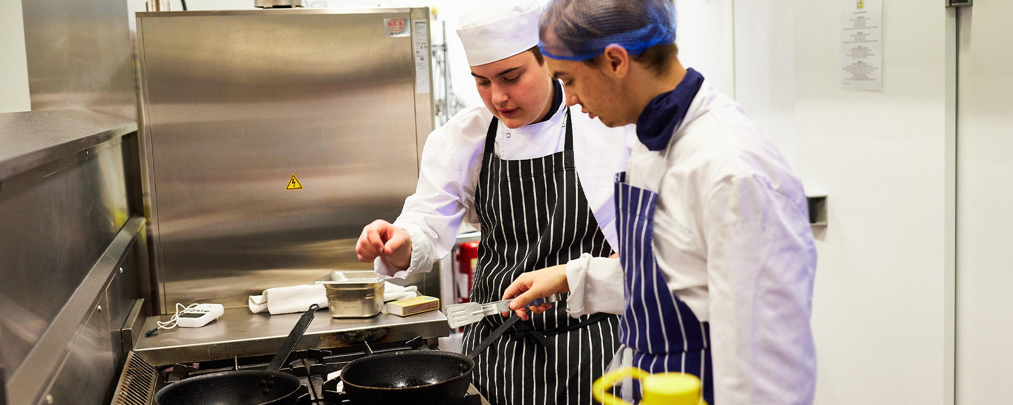 Two students preparing some food in a kitchen