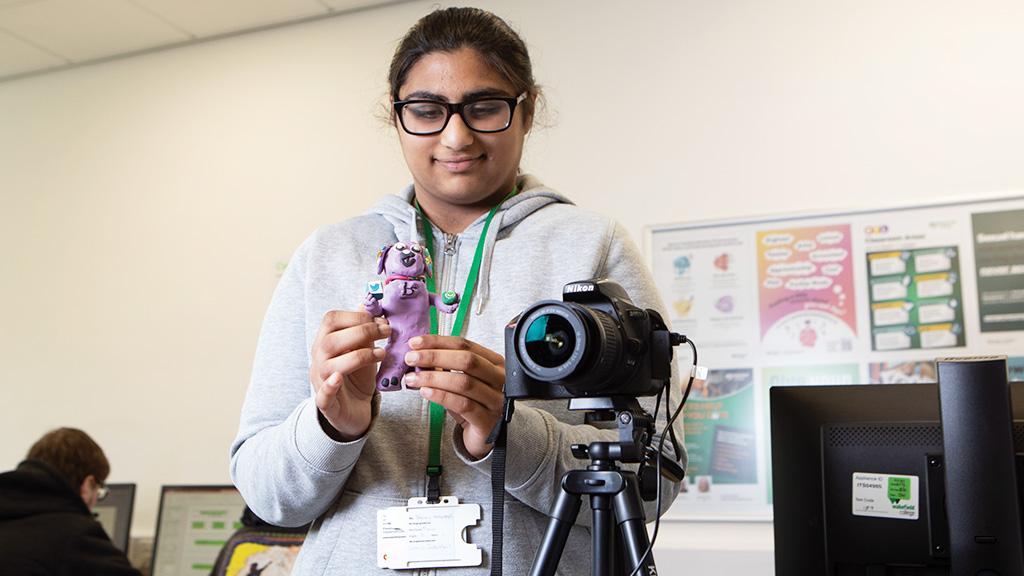 Student holding a model to film as part of a video