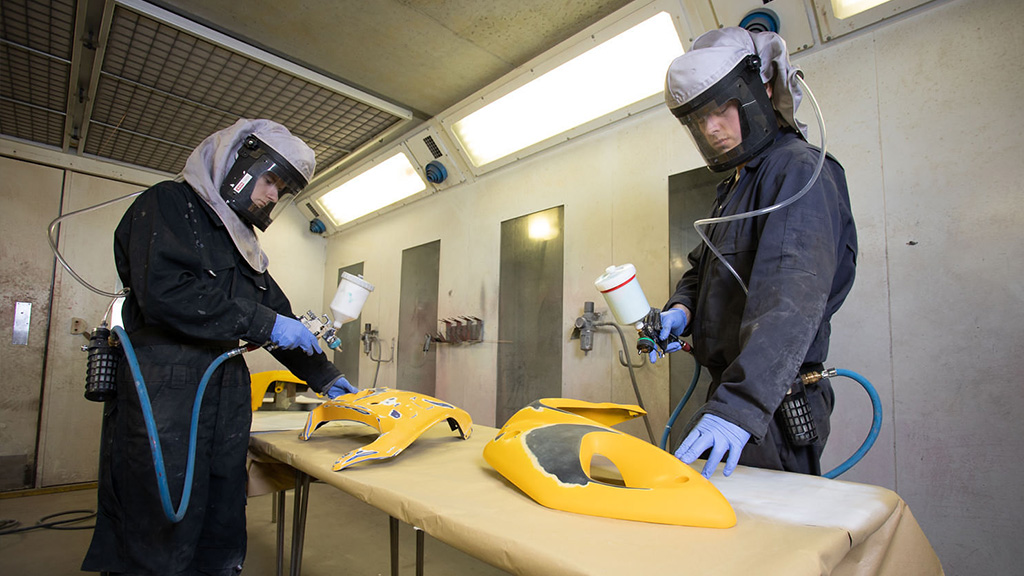 Students spray car parts in spray booth