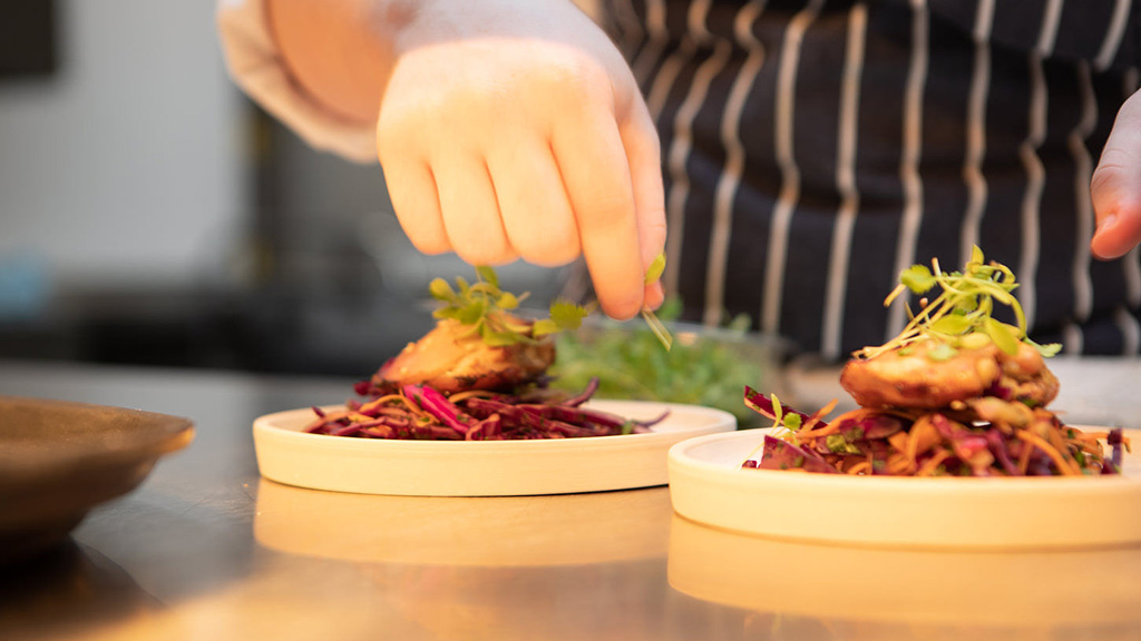 Student plating up dishes for serving 