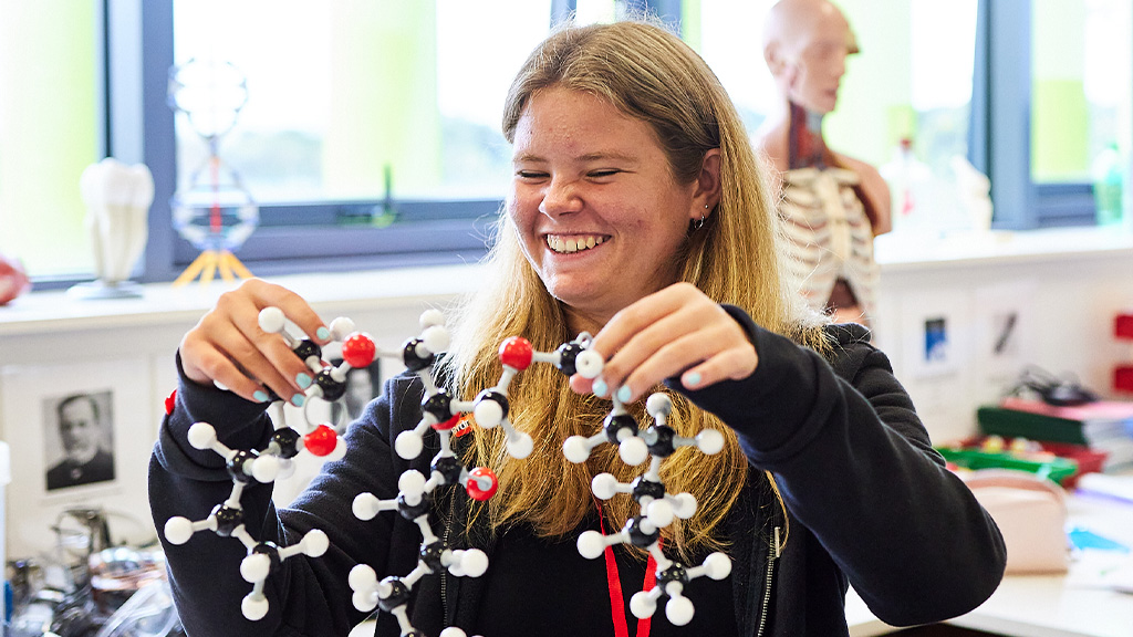 Student in lab coat using scientific equiptment