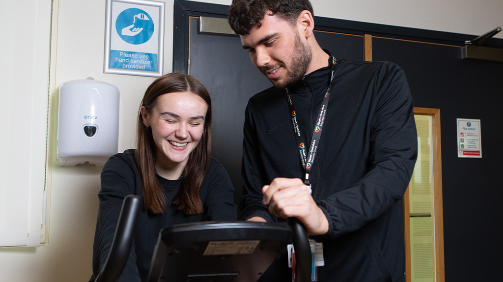 Student on exercise bike with teacher instructing them